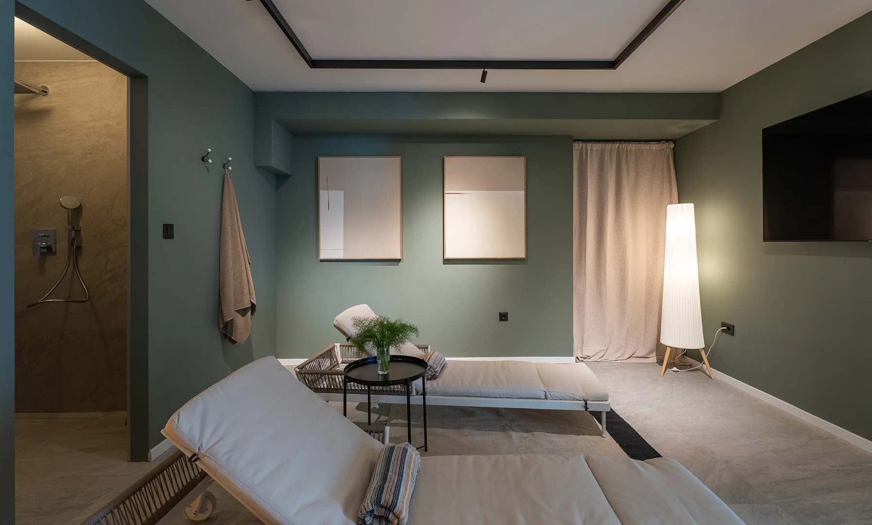 A modern lounge with a low seating area, framed artwork, and a floor lamp.