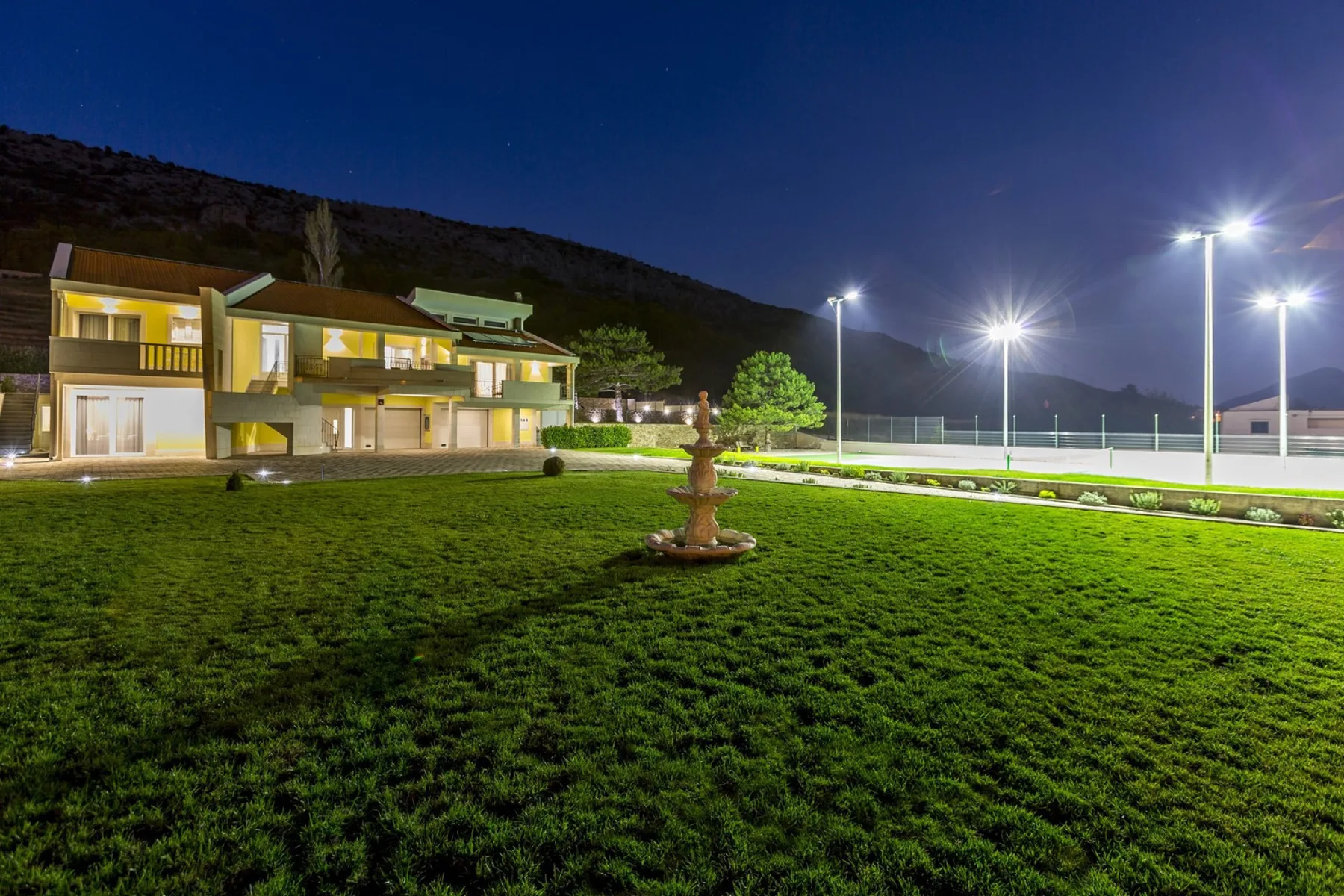 Se ven un edificio moderno y una cancha iluminada por la noche.