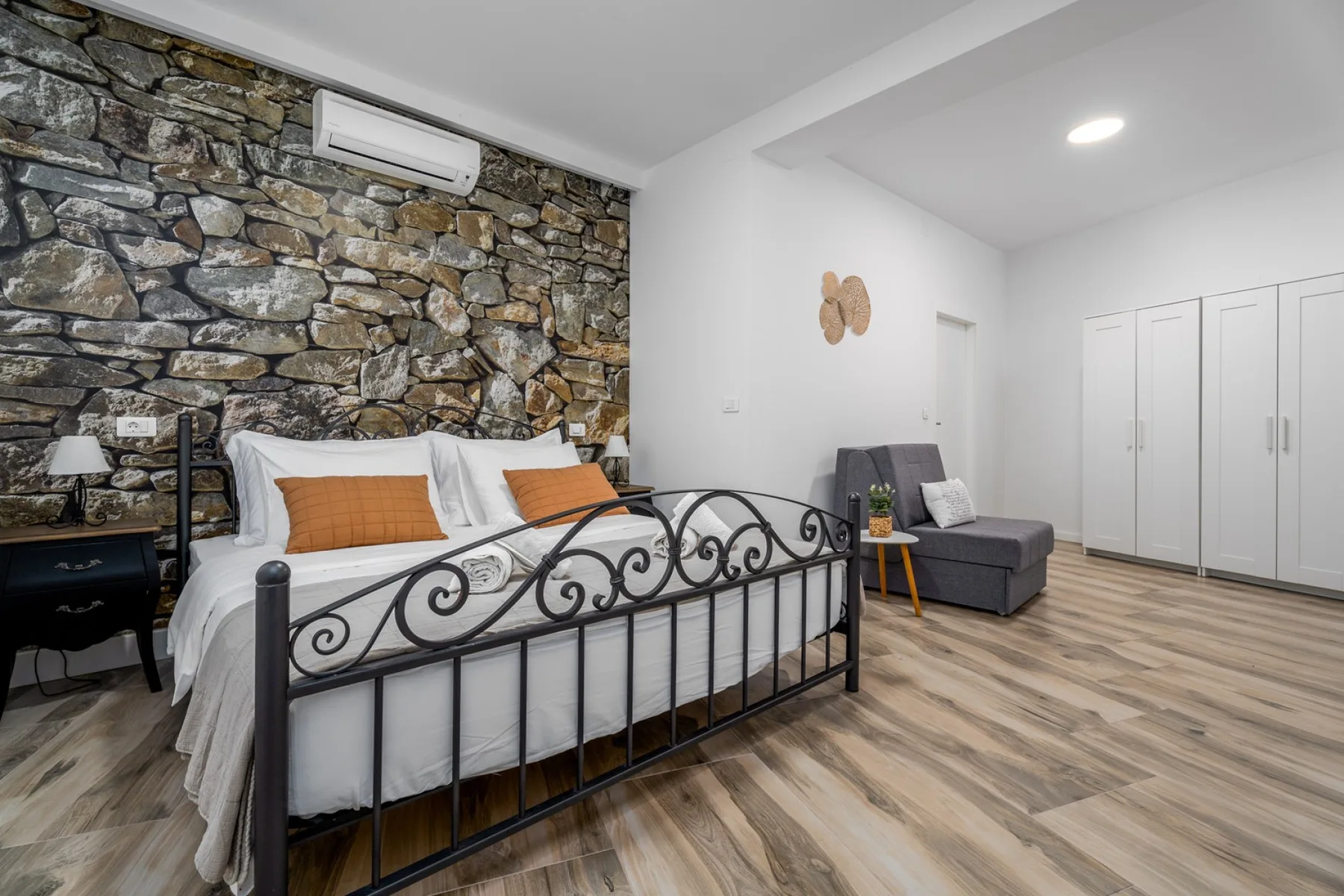Un dormitorio con una cama junto a una pared de piedra y una zona de estar.