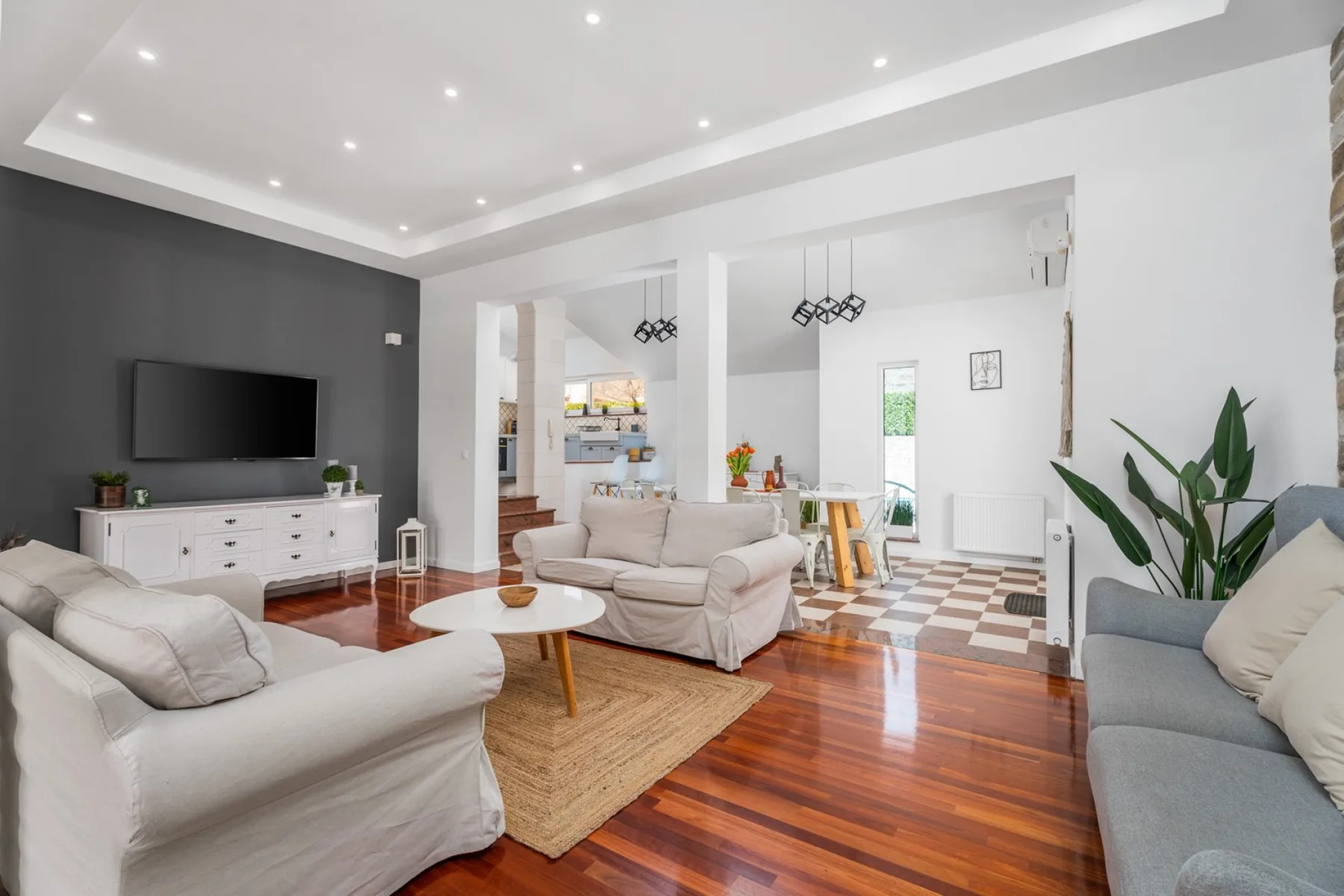 Una sala luminosa con asientos, un televisor y un comedor abierto.