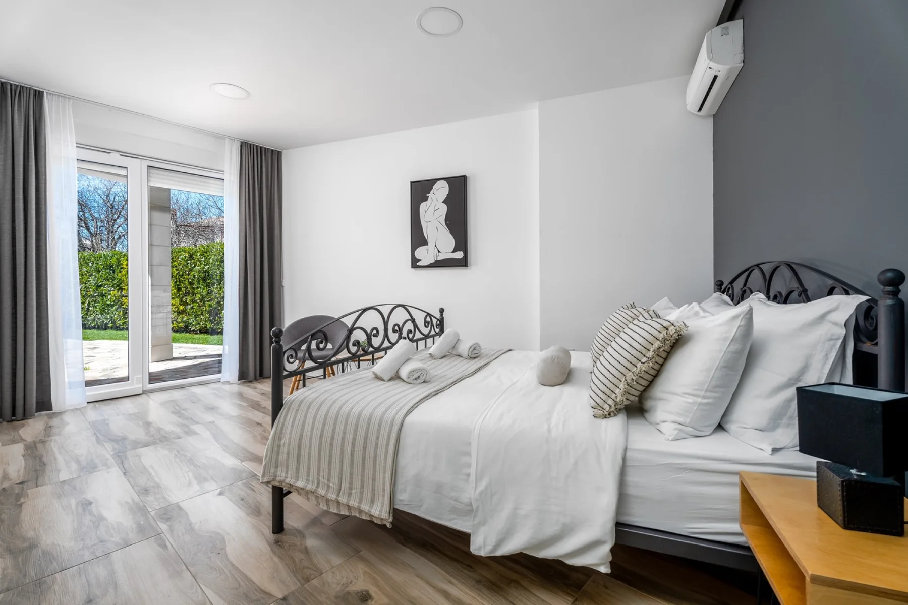 Un dormitorio luminoso con camas bien arregladas y ventanales que dan a zonas verdes.