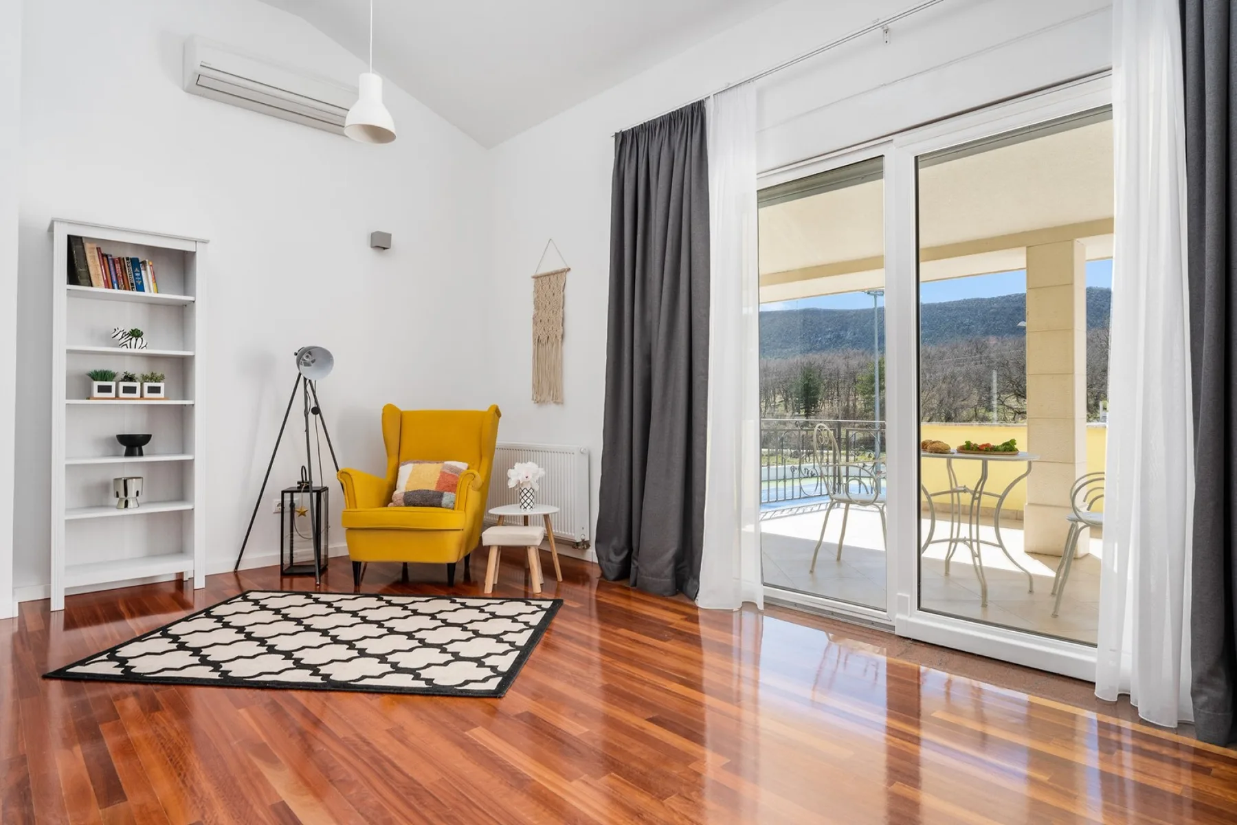 Una luminosa sala de estar con un sillón amarillo junto a puertas corredizas de vidrio.
