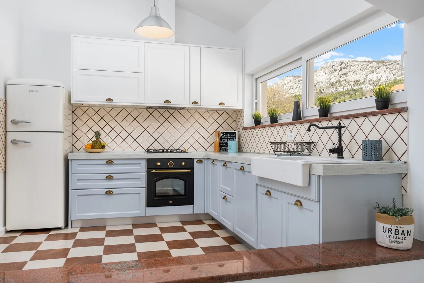 Una cocina luminosa con gabinetes blancos, un salpicadero de azulejos y una ventana grande.