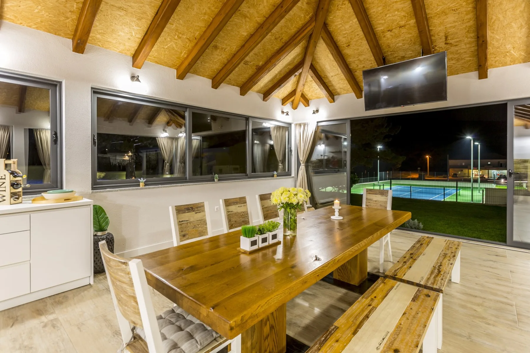 Un comedor con una larga mesa de madera bajo un techo abovedado de vigas.