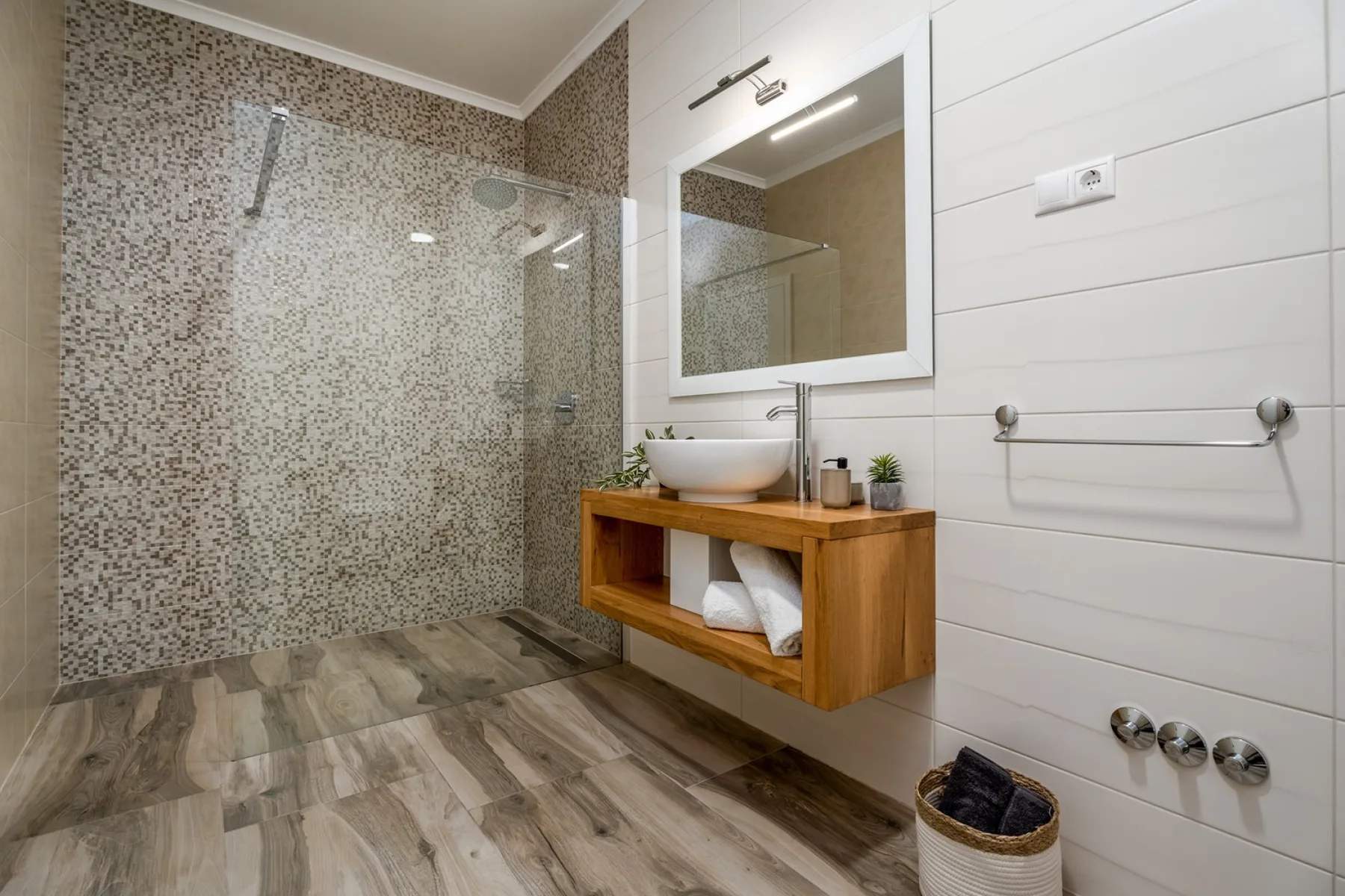 Un baño moderno con ducha de cristal y un mueble de madera.