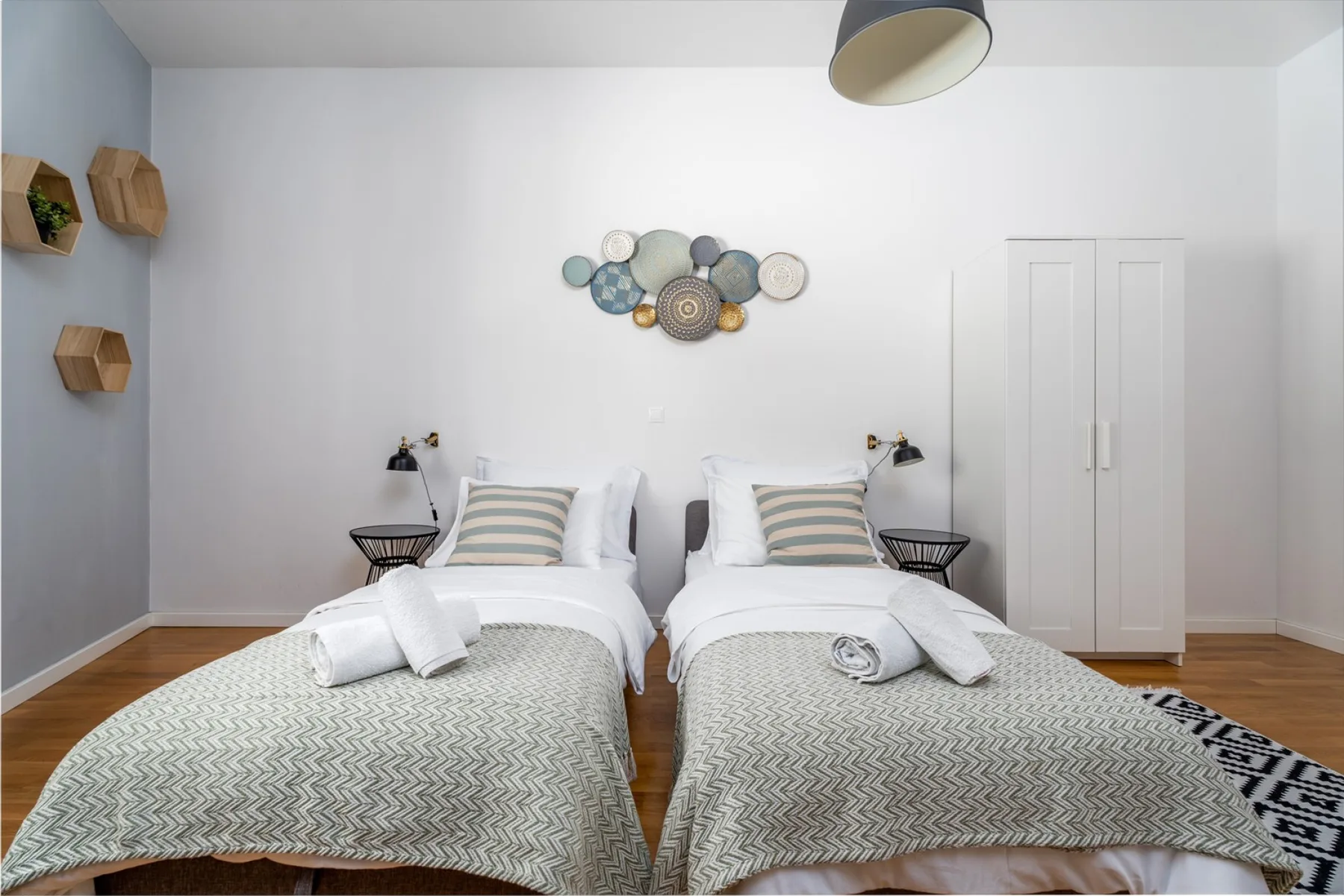 Un dormitorio con dos camas individuales bien arregladas bajo adornos circulares en la pared.