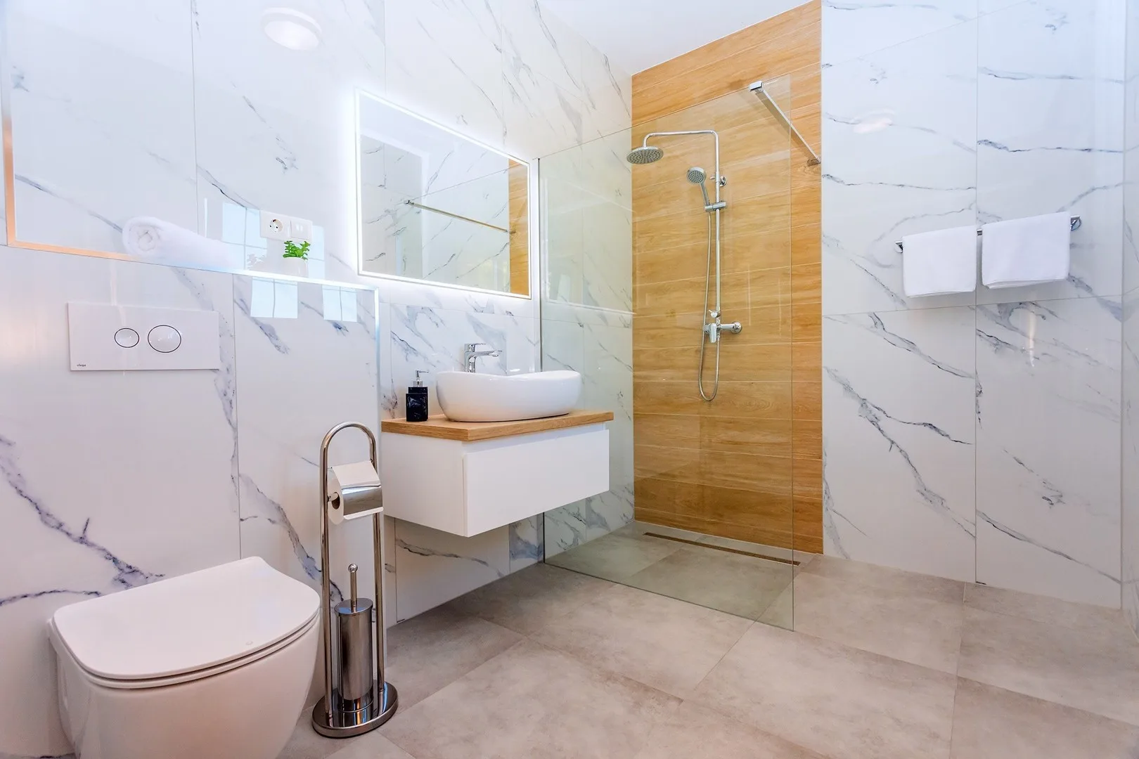A modern bathroom with a sink, toilet, and glass shower.