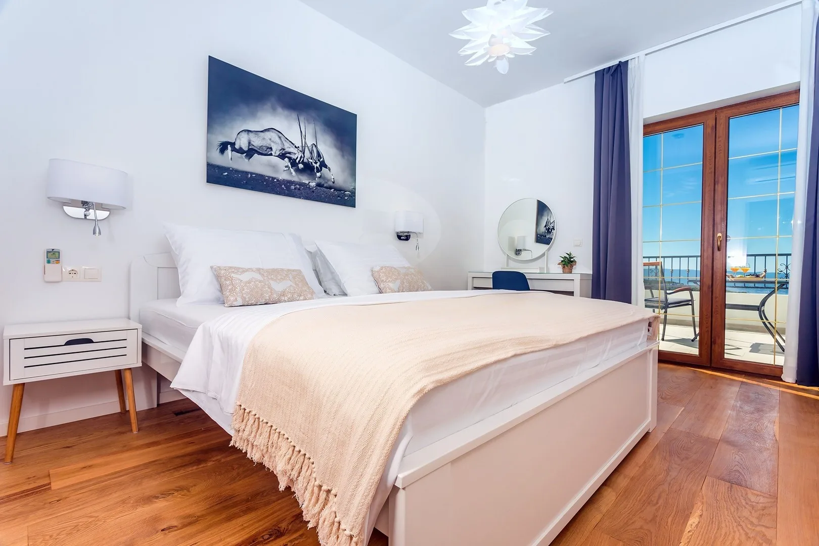 A bright bedroom with a large bed and glass doors opening onto a balcony.