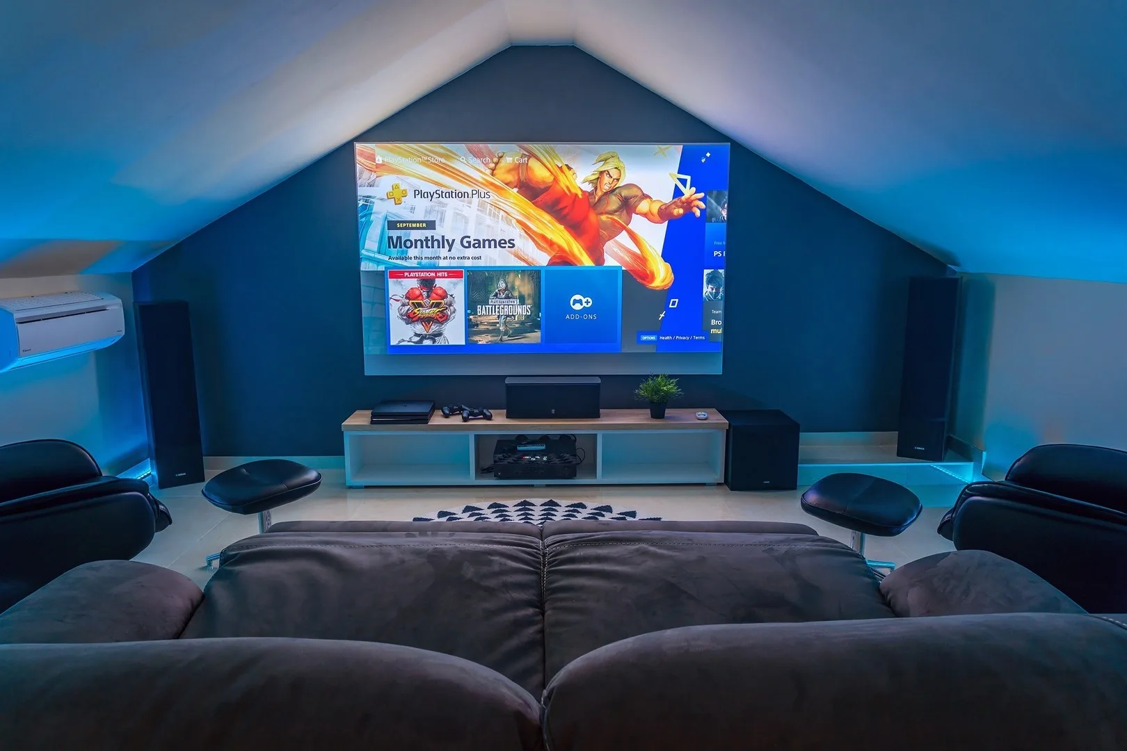 A media room with a large television facing cushioned seating.