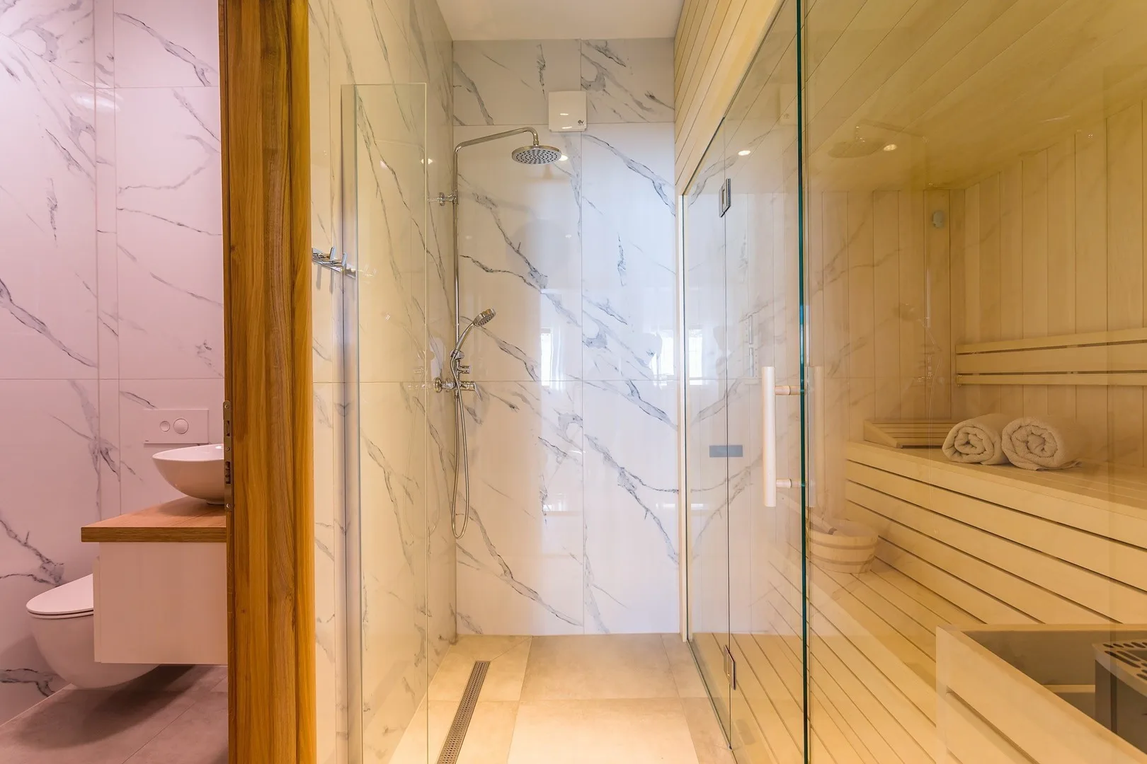 A bathroom with a glass shower and a wooden sauna.