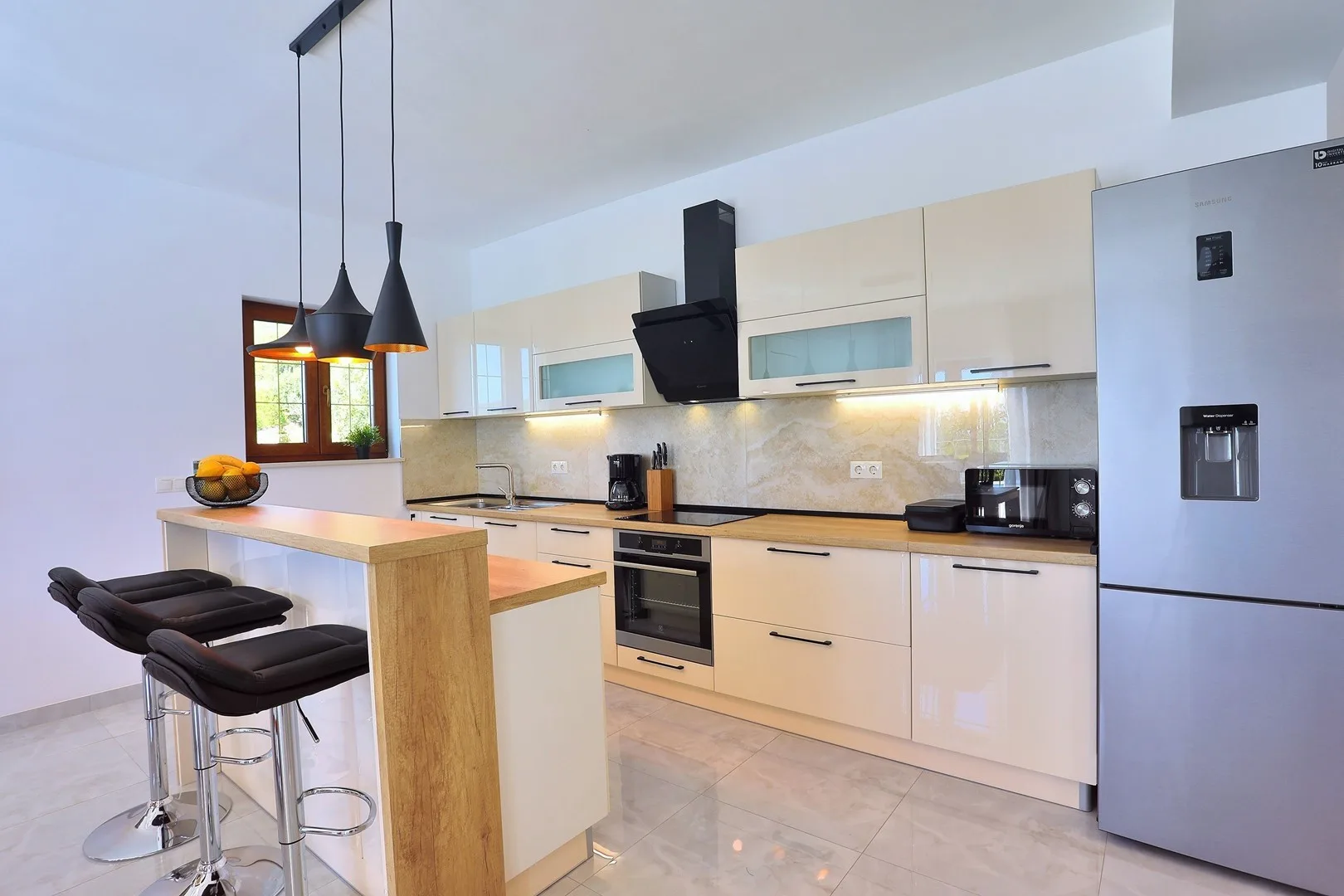 A modern kitchen with a breakfast counter and pendant lights.