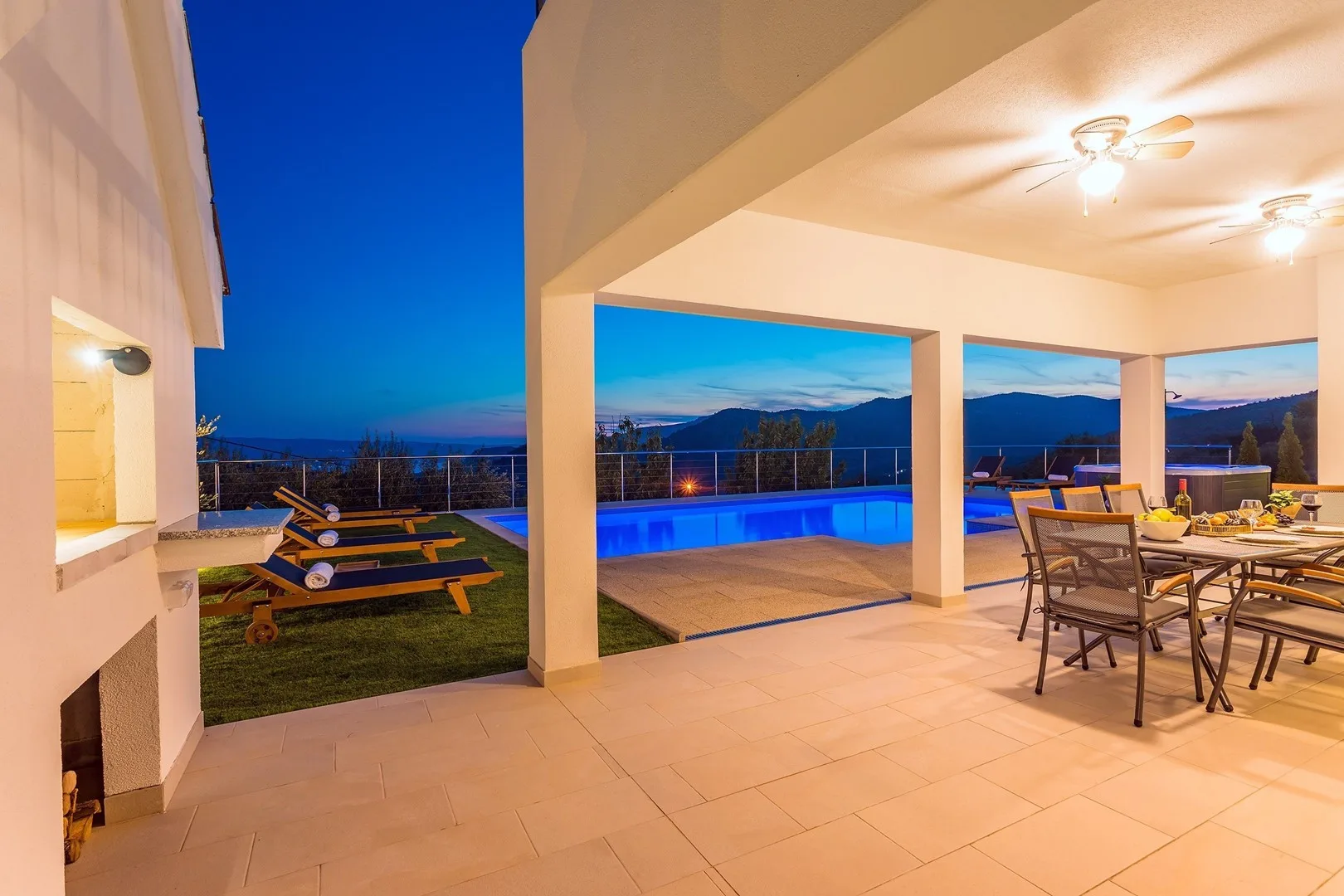 A covered patio opens onto a swimming pool and mountain views.