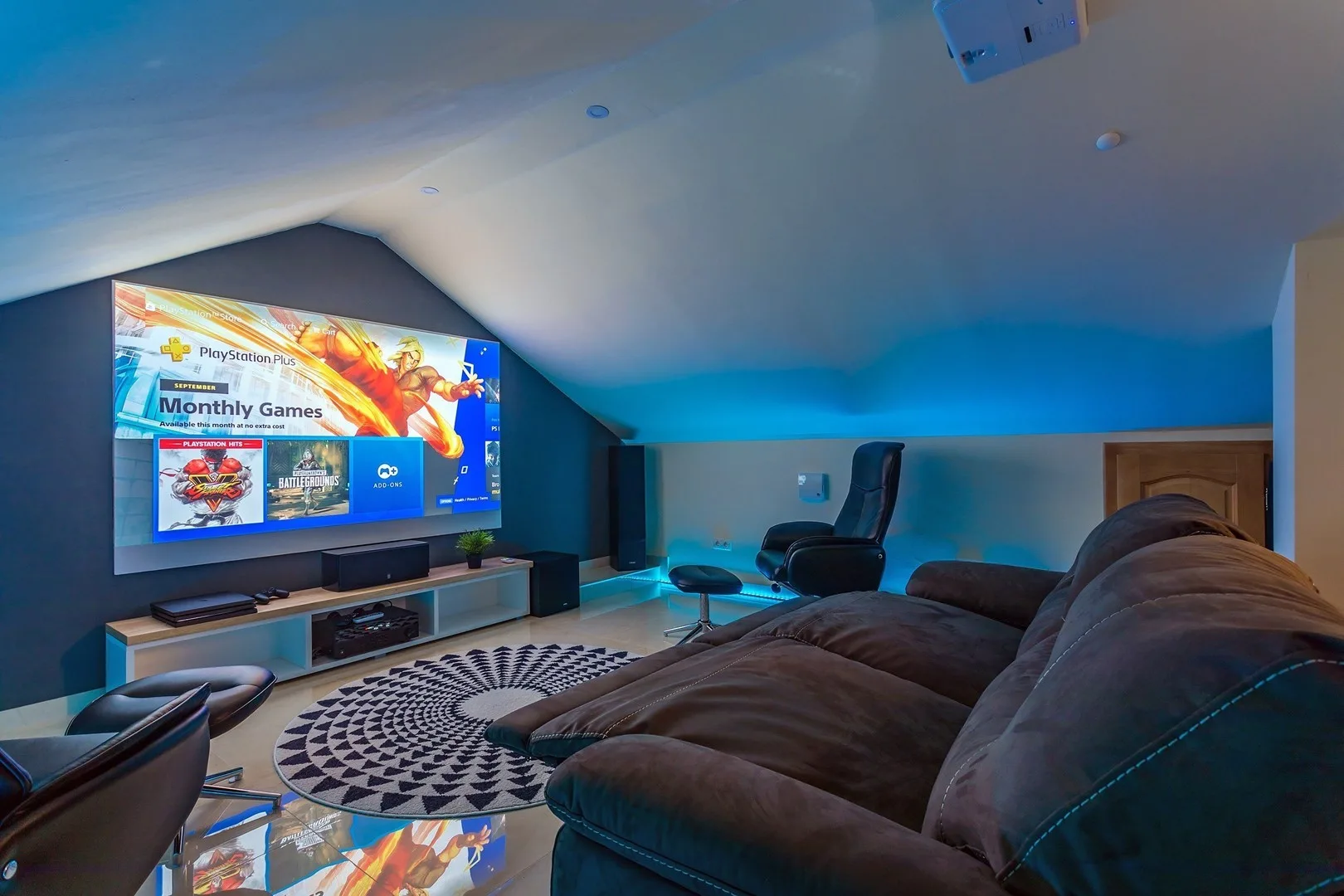A media room with a large television, sectional seating, and a patterned rug.