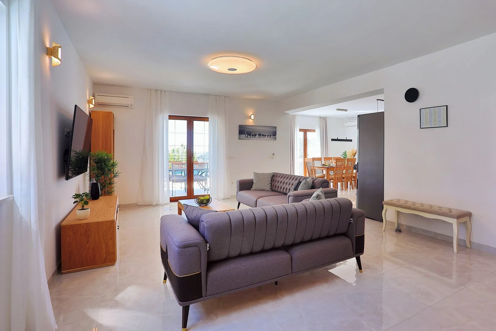 A living room with seating, a television, and an open dining area.