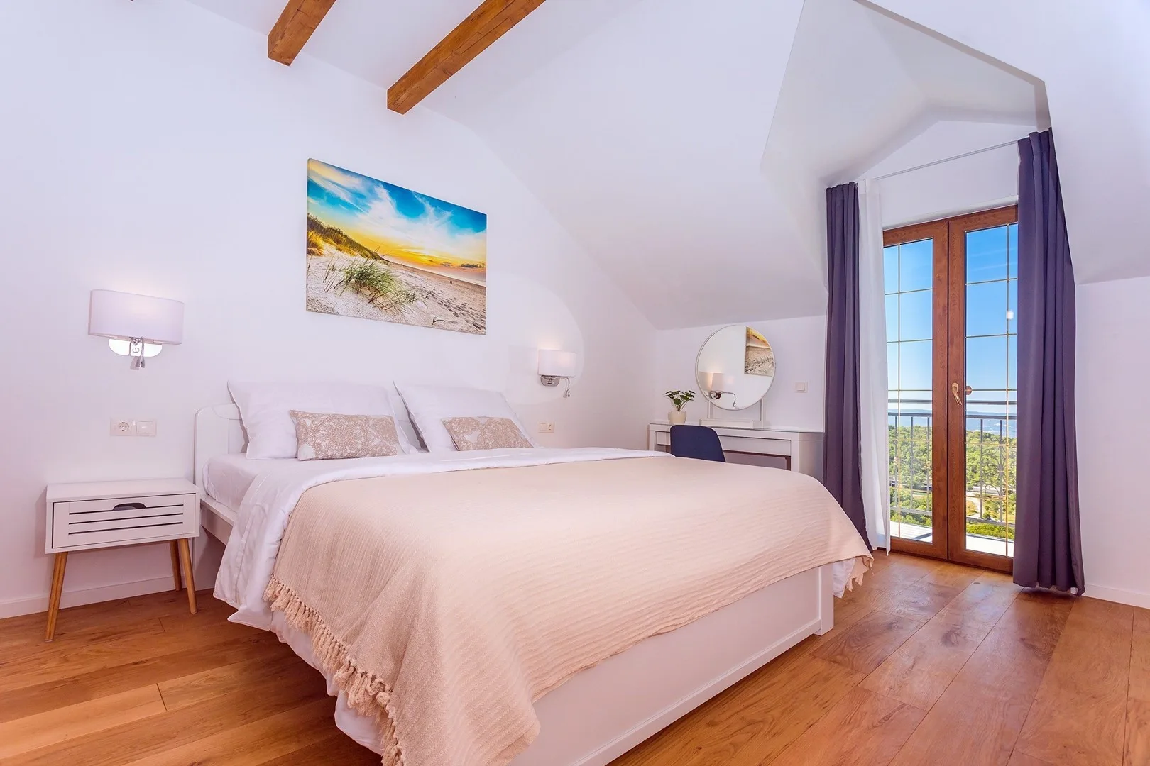 A bright bedroom with a large bed and glass doors opening to a balcony.