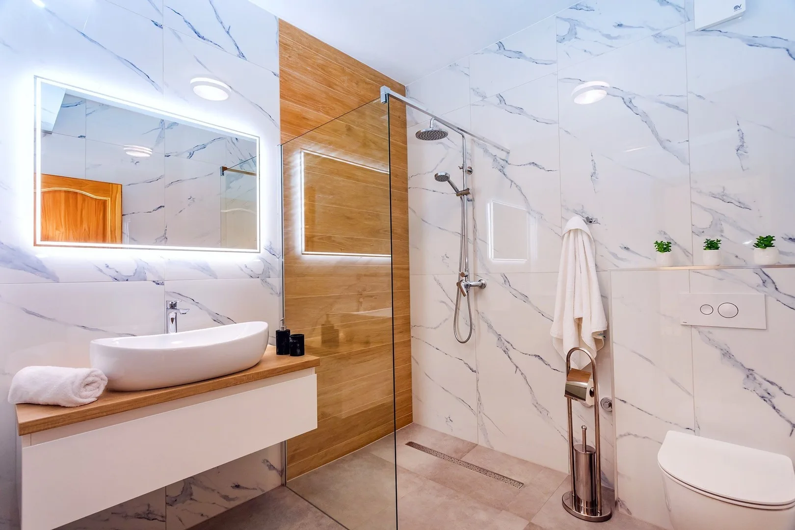 A bright bathroom with a sink vanity, glass shower, and toilet.