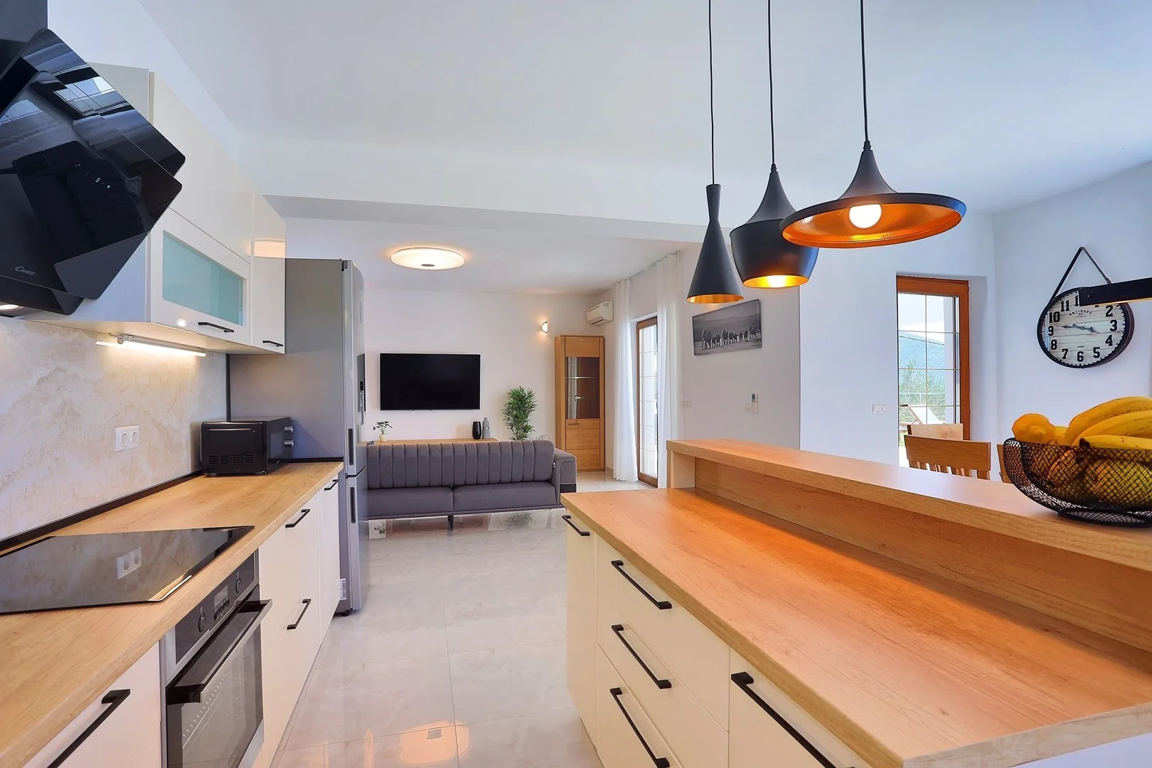 An open kitchen and living area with a long wooden countertop and seating.