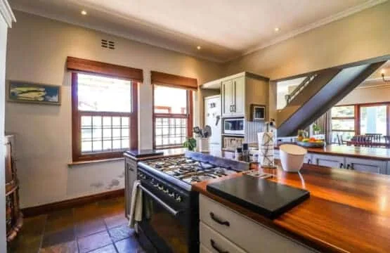 A bright kitchen with a large stove, wood countertops, and several tall windows.