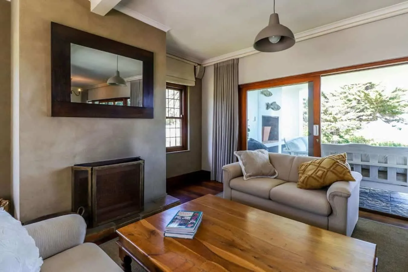 A living room with a beige sofa, wooden coffee table, fireplace, and large glass doors opening to a balcony.