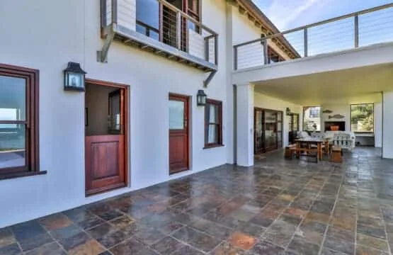A tiled courtyard opens onto a covered dining area, with wooden doors and an upper balcony.