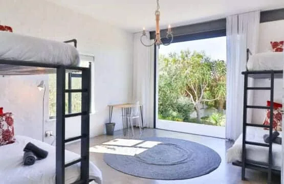 A bright bedroom with bunk beds and a large window overlooking greenery.
