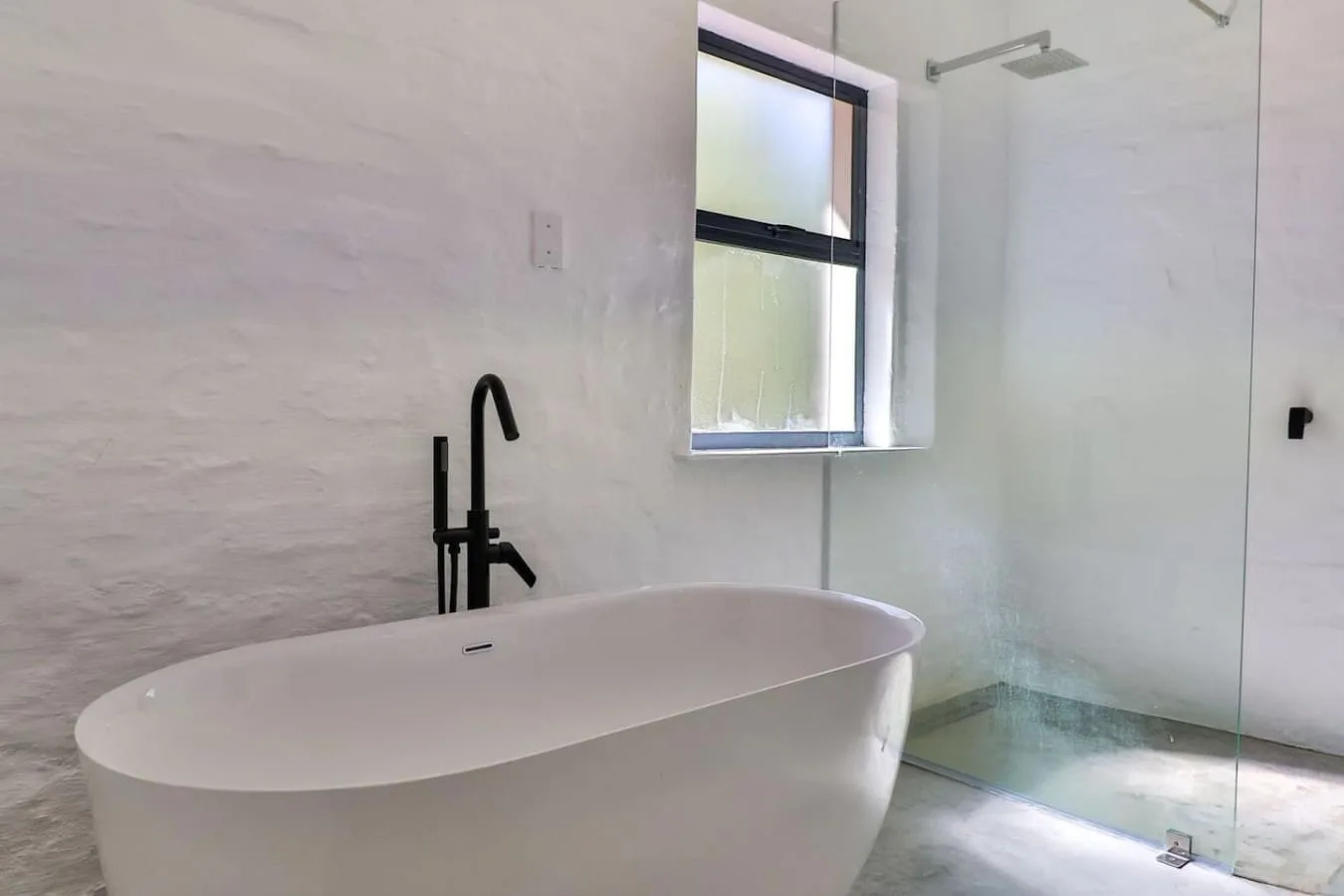 A bathroom with a freestanding bathtub beside a glass shower.