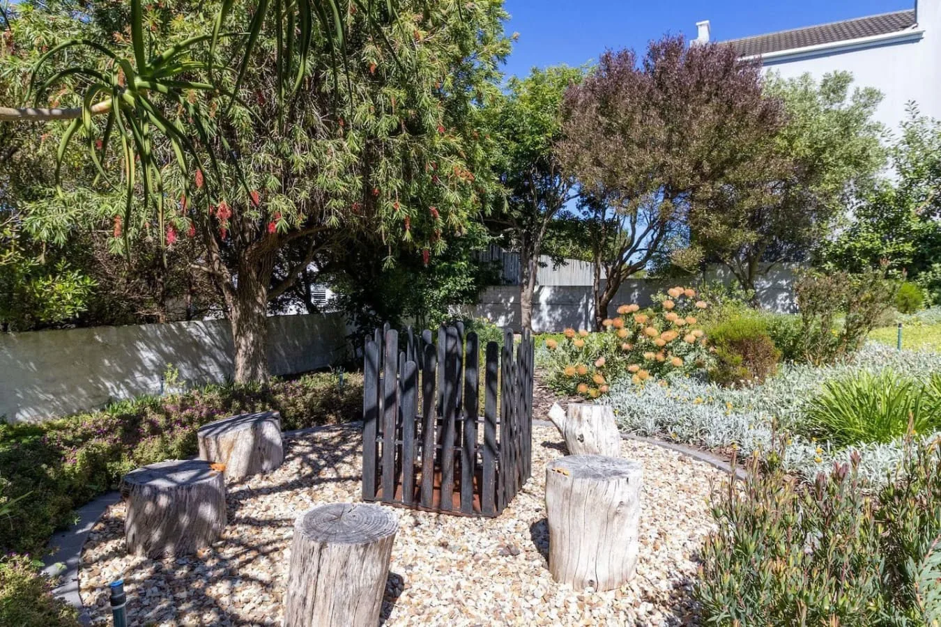 A landscaped garden with flowering shrubs and rustic wooden seating.