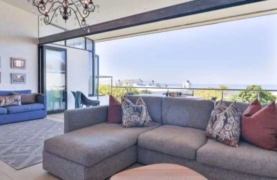 A bright living room opens onto a balcony, with seating facing the view.