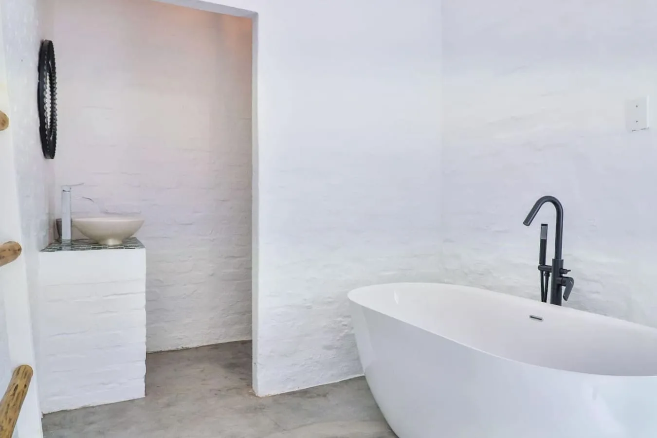 A bathroom with a freestanding bathtub and a small sink.