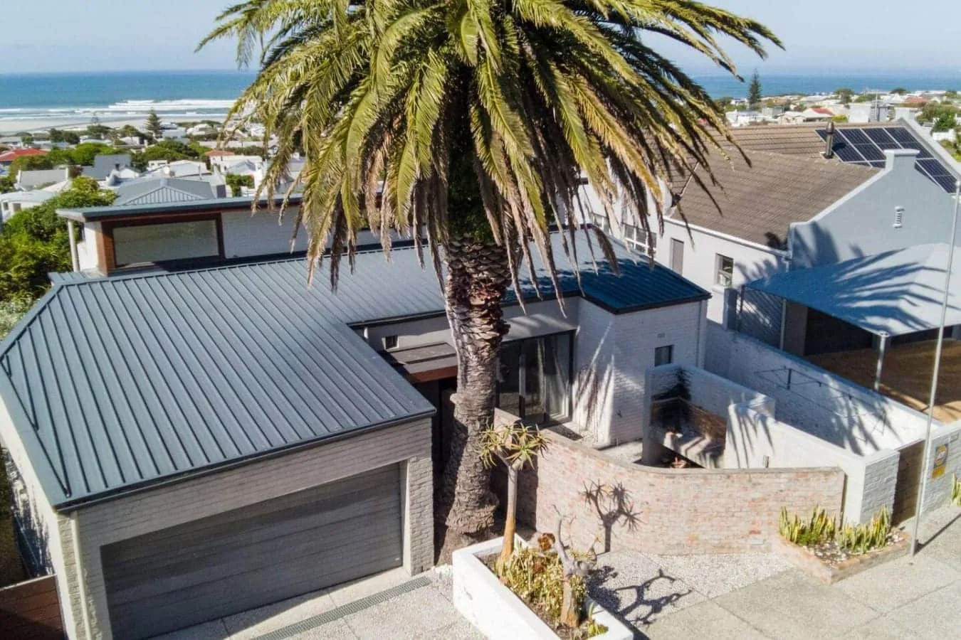 Aerial view of modern homes with a tall palm tree in the foreground.