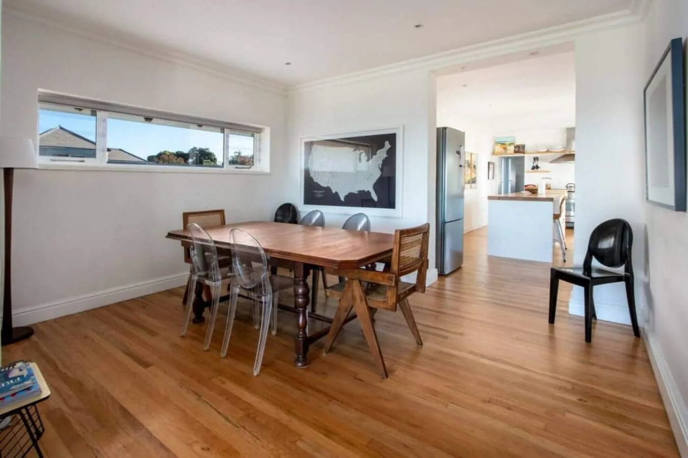 Comedor con una mesa de madera y sillas junto a una cocina luminosa.