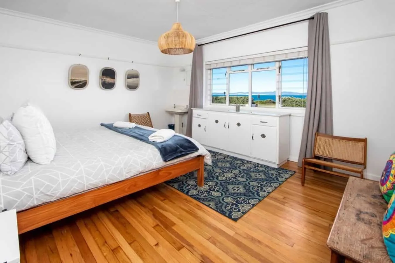 Un dormitorio con una cama, una alfombra estampada y una ventana amplia con vistas al agua.