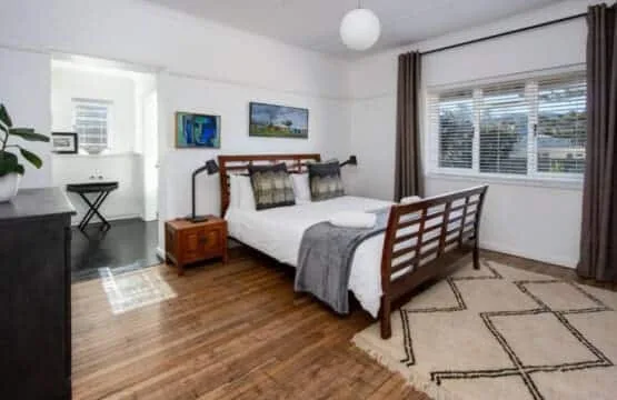 Un dormitorio con una cama de madera y una ventana grande.