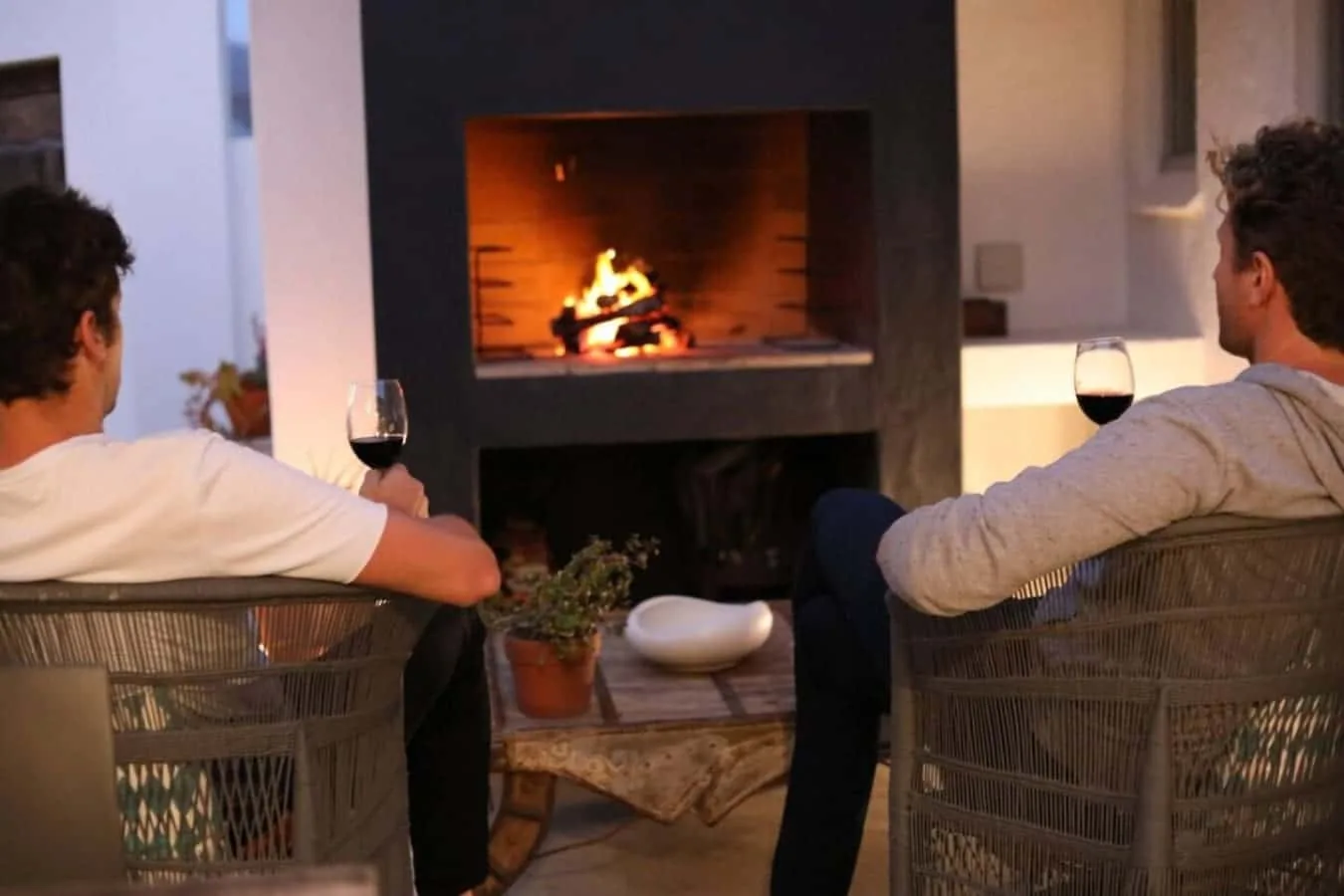 Dos personas están sentadas junto a una chimenea encendida en una sala de estar.