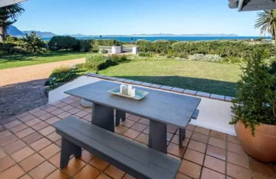 Un patio exterior con una mesa de picnic da a un césped y al mar.