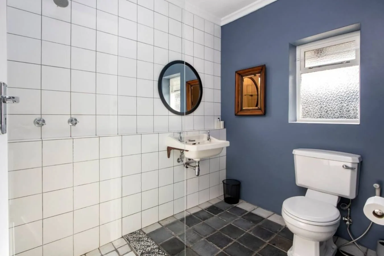 Un baño alicatado con lavabo, inodoro y ventana esmerilada.