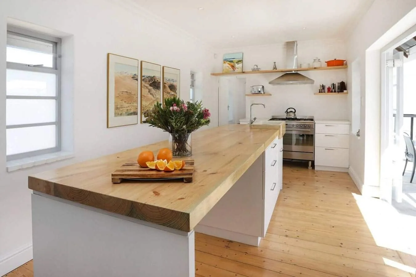 Una cocina luminosa con una larga isla de madera y zona de cocción.