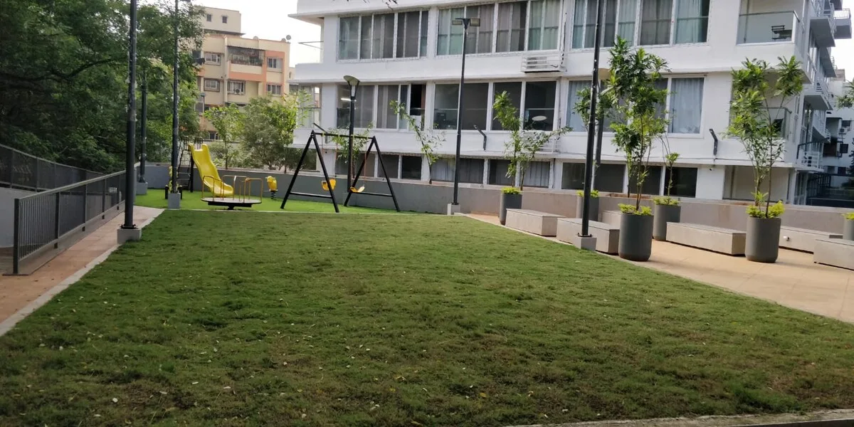 Zona común: Un patio ajardinado con césped, juegos infantiles y edificios alrededor.