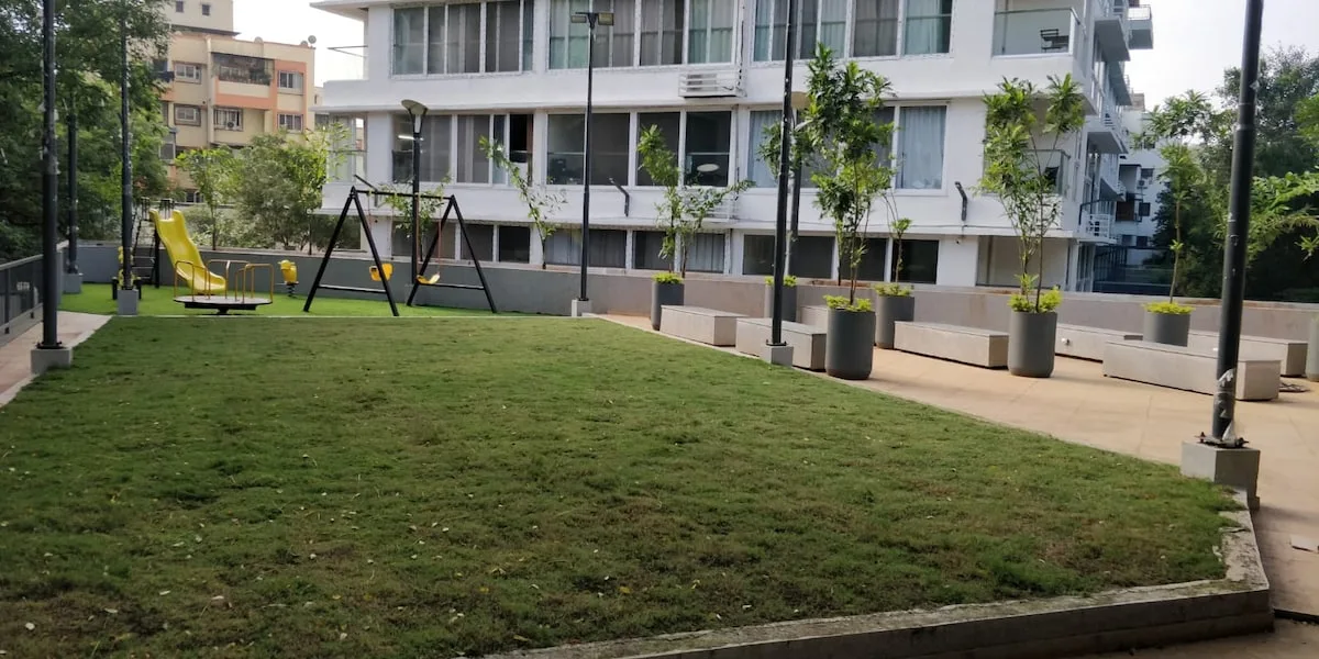 Zona común: Una zona de césped junto a un camino pavimentado y un edificio de apartamentos.