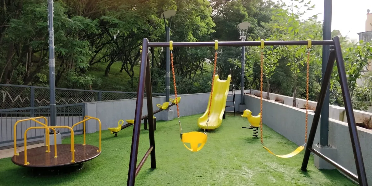 Zona común: Un área de juegos al aire libre con columpios y un tobogán amarillo.