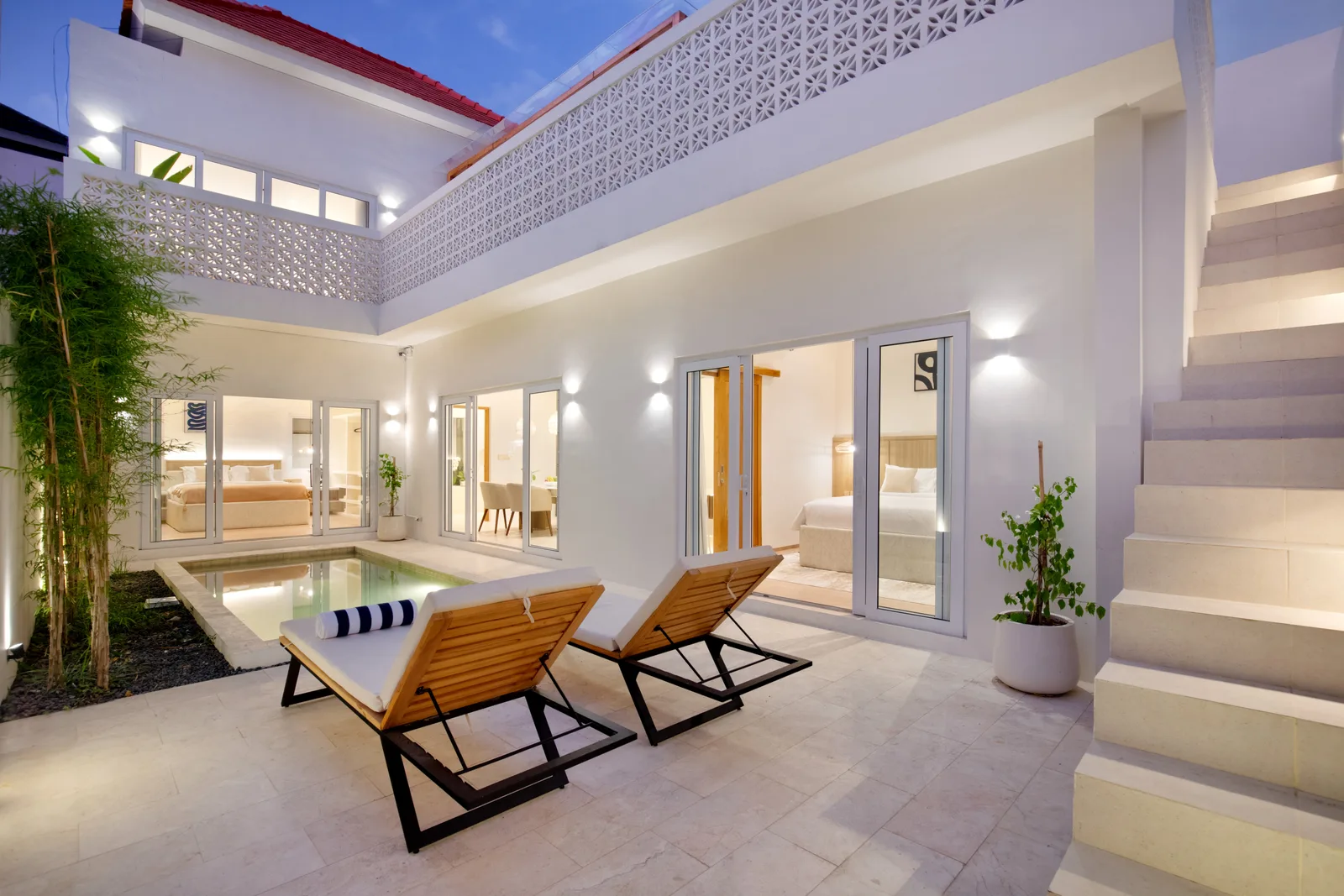 A bright courtyard patio with two lounge chairs beside a small pool.