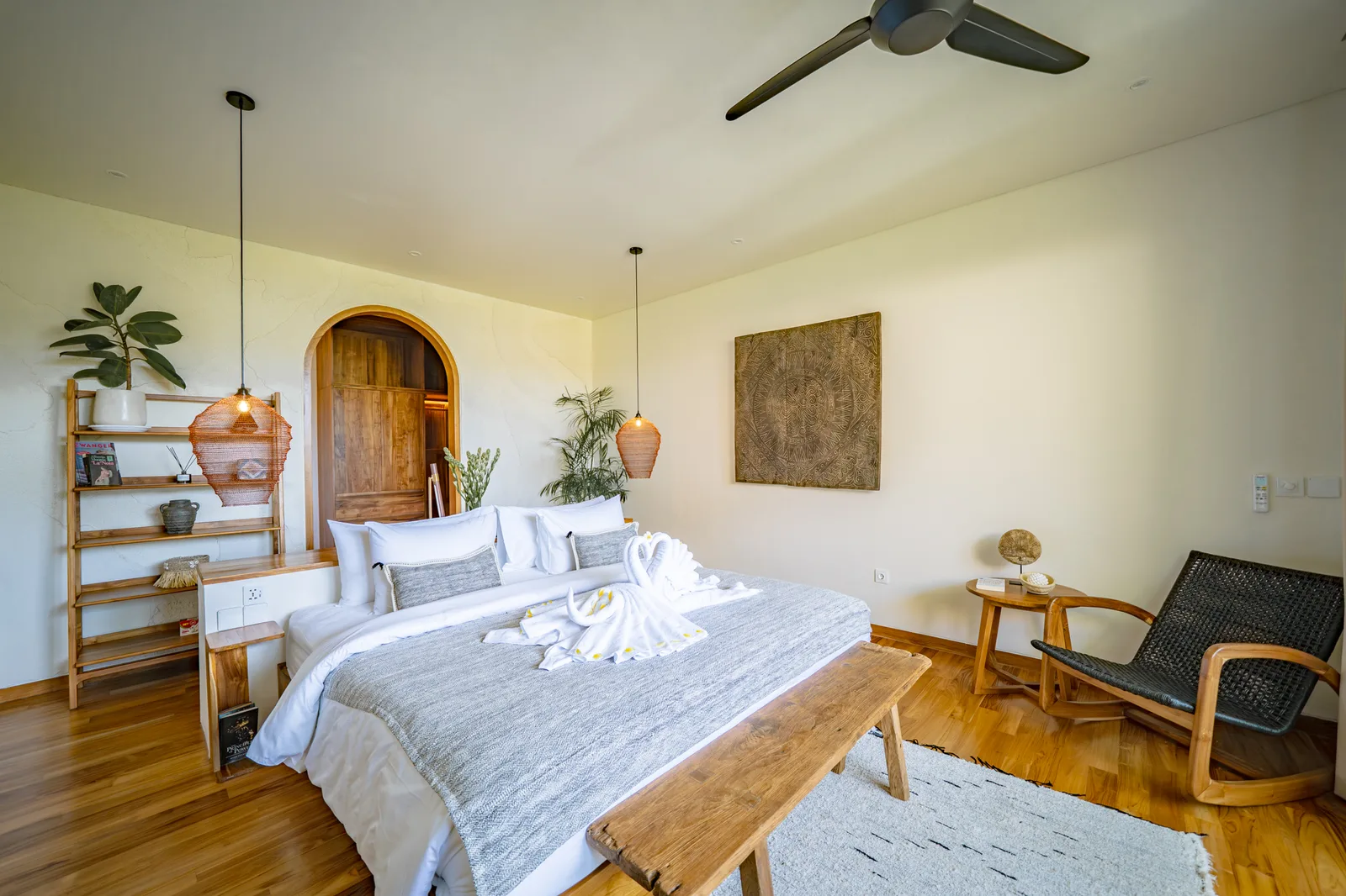 Un dormitorio luminoso cuenta con una cama grande con toallas dobladas, muebles de madera y un ventilador de techo.