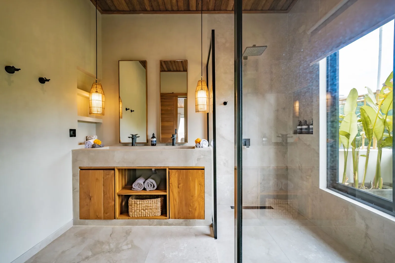 A modern bathroom features a double-sink vanity, warm wood cabinets, and a glass-enclosed shower.