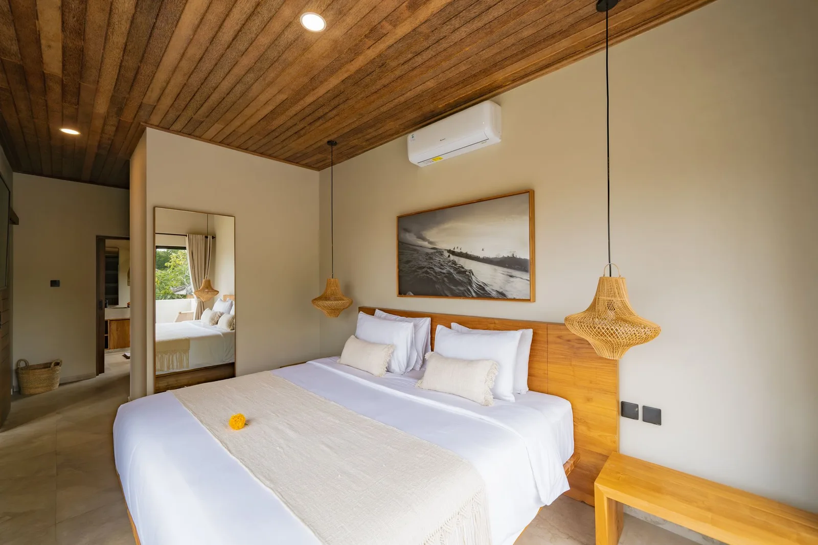 A bedroom with a white double bed, wooden headboard, woven pendant lights, and a wood-plank ceiling.
