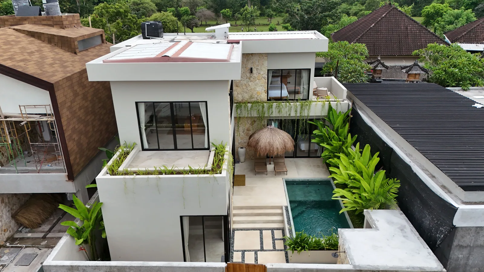 A modern white house with large windows, rooftop terraces, and a narrow outdoor pool.