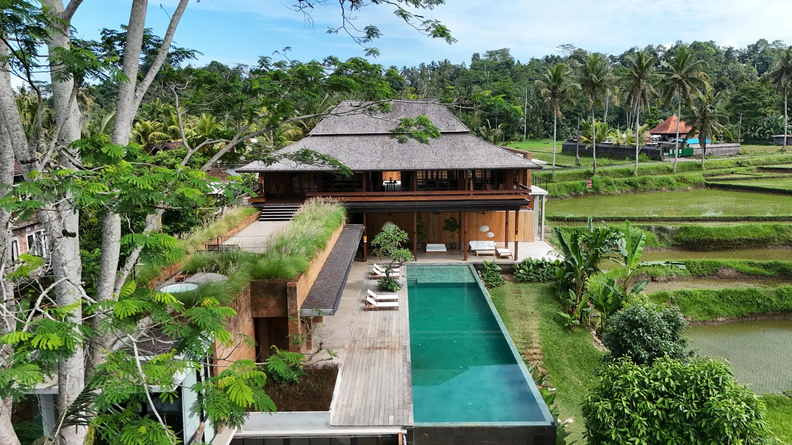 Un edificio en un entorno tropical da a una piscina larga entre vegetación exuberante.