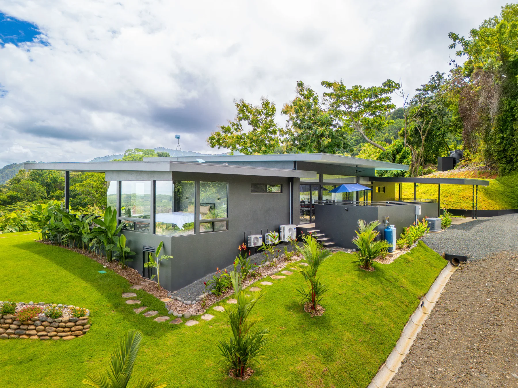Modern house with large windows sits in a landscaped green garden.