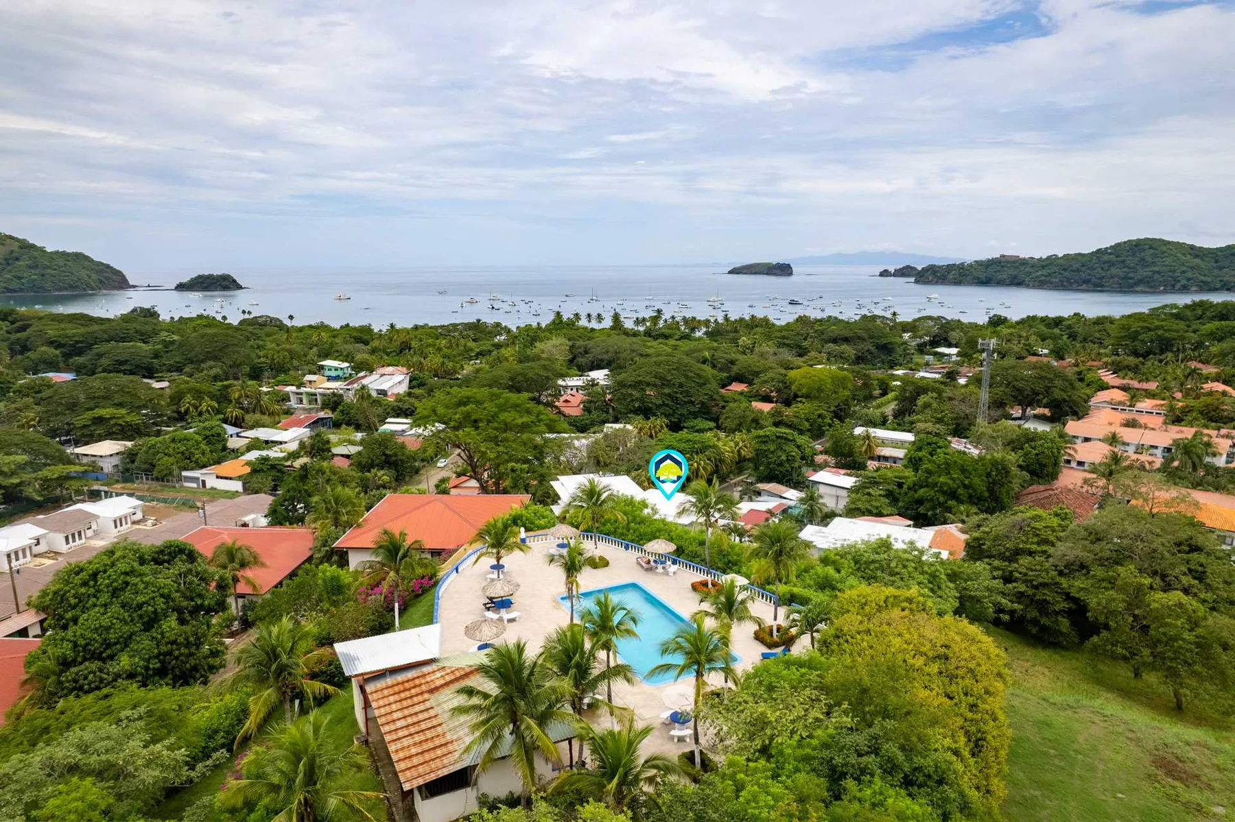 Shared amenity: Aerial view of a tropical coastal settlement with a pool among the greenery.