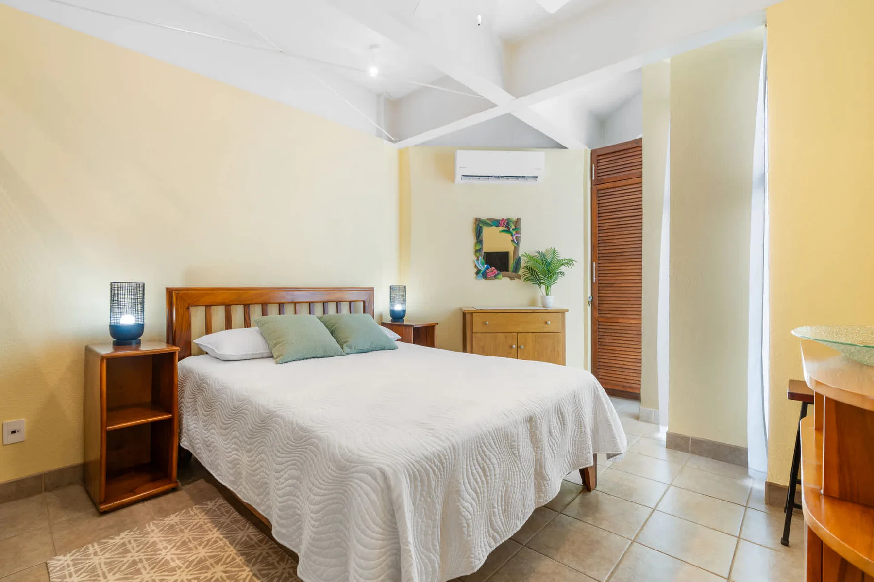 A bedroom with a neatly made bed, bedside tables, and a dresser.