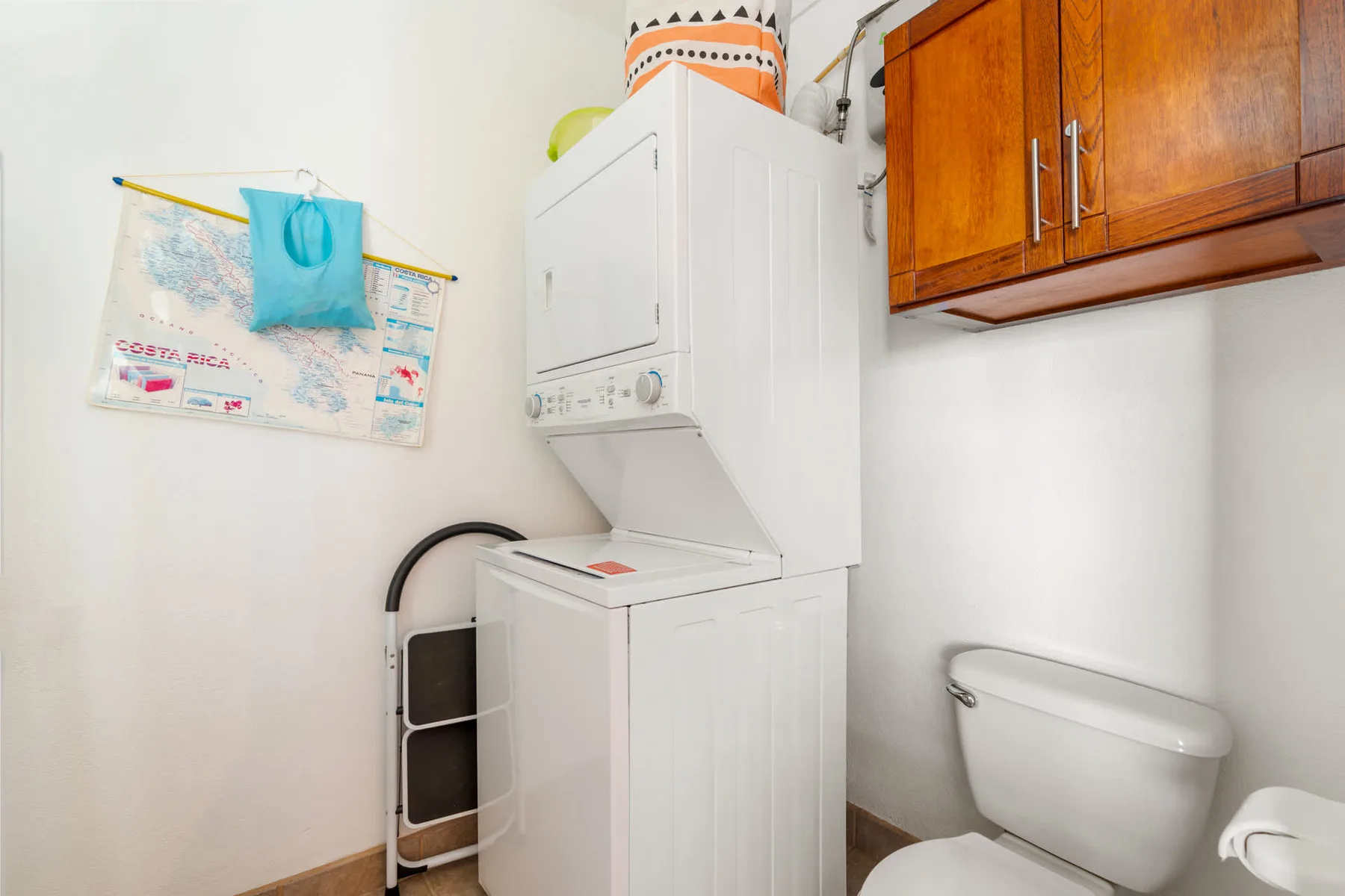 A laundry area with a stacked washer and dryer beside a toilet.